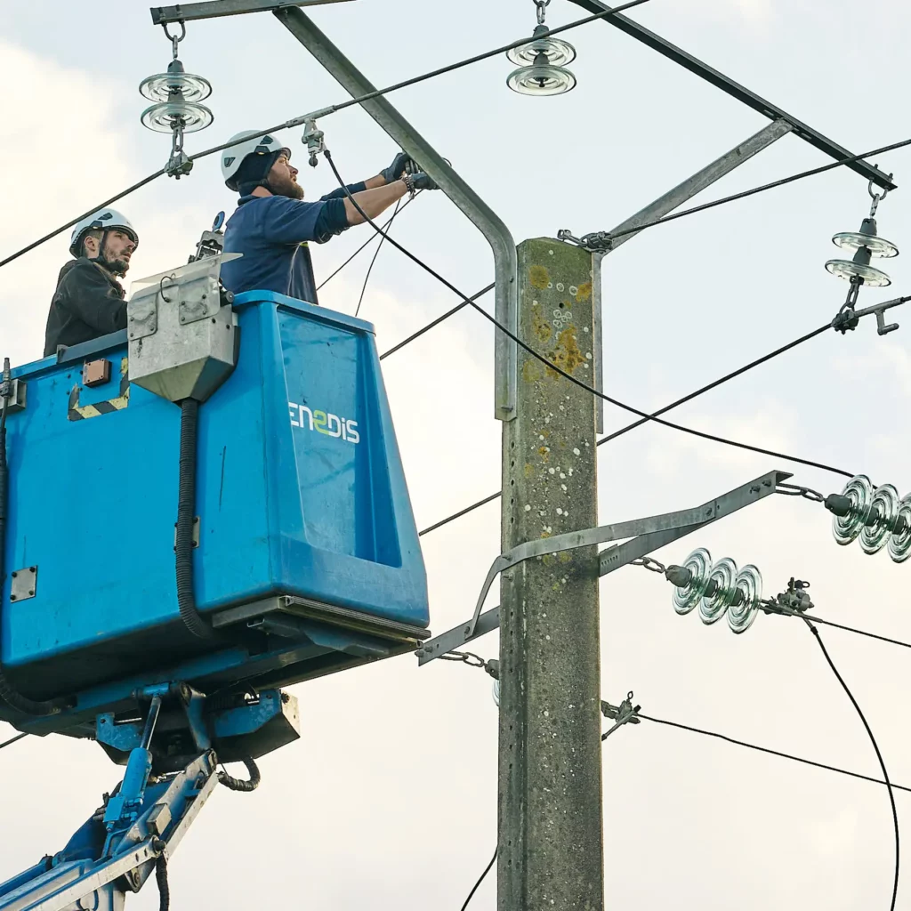 Deux techniciens Enedis intervenant sur des lignes haute tension depuis une nacelle
